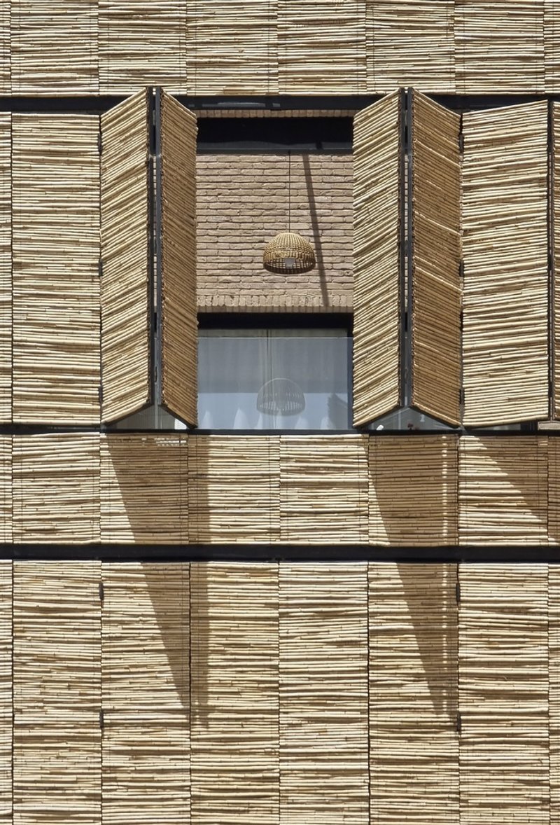 Facade detail showing horizontal reed shutters flanking a glazed opening with visible pendant light inside