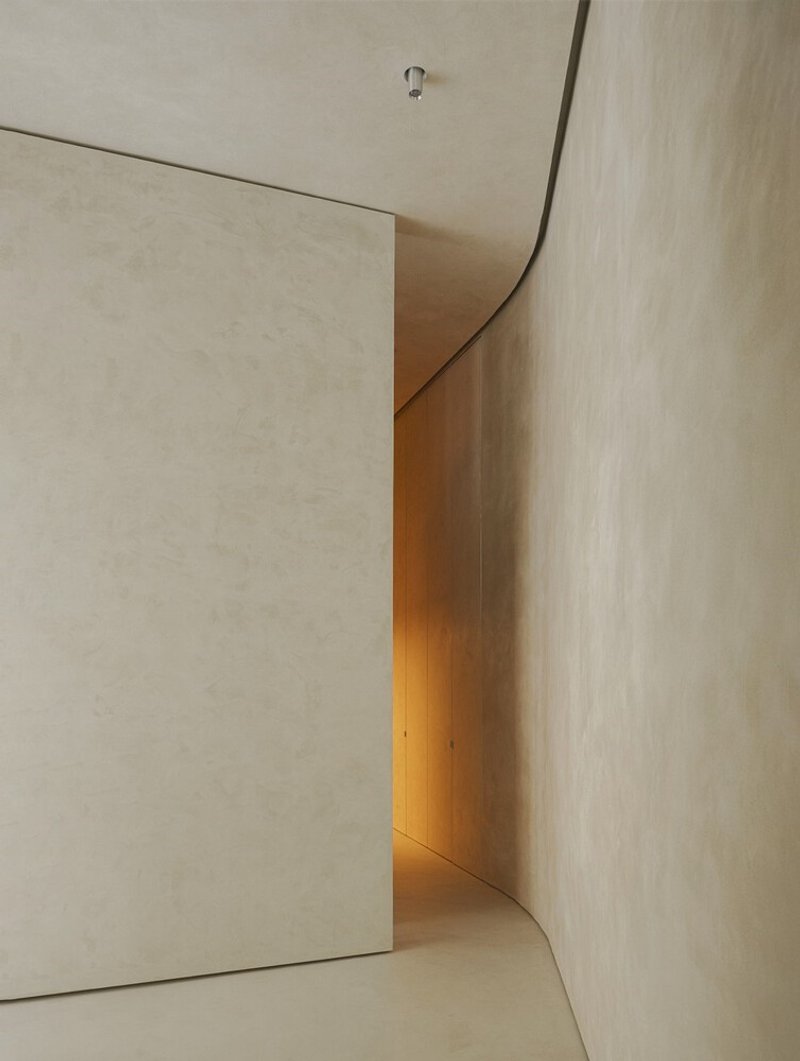 Curved corner passage with concealed lighting revealing a transition between plaster surfaces
