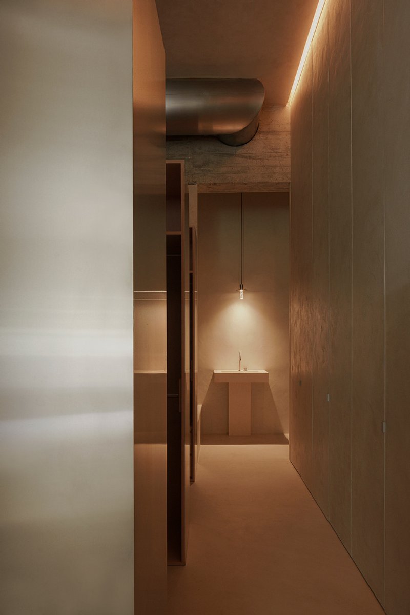 Corridor view toward a stepped altar-like platform illuminated by a single pendant light