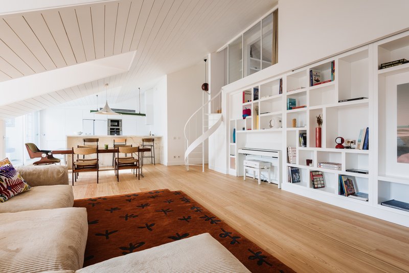Open living and dining area with white spiral stair and built-in shelving divider
