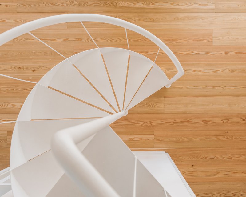 Overhead view of white spiral stair treads with oak flooring below