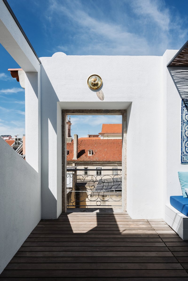 Rooftop terrace with timber decking framing a view of orange-tiled rooftops beneath clear blue sky