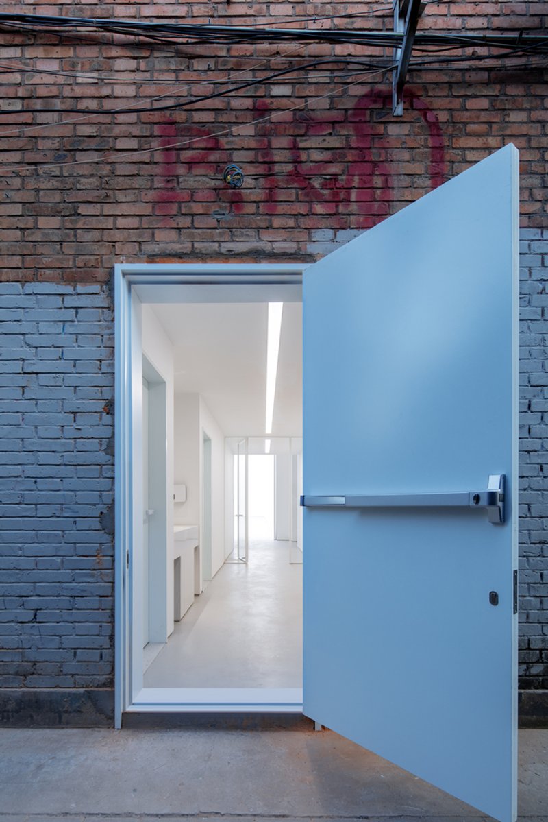 Corridor and bridge: second-floor passage overlooking the ground floor, skylights, tall windows to the trees outside