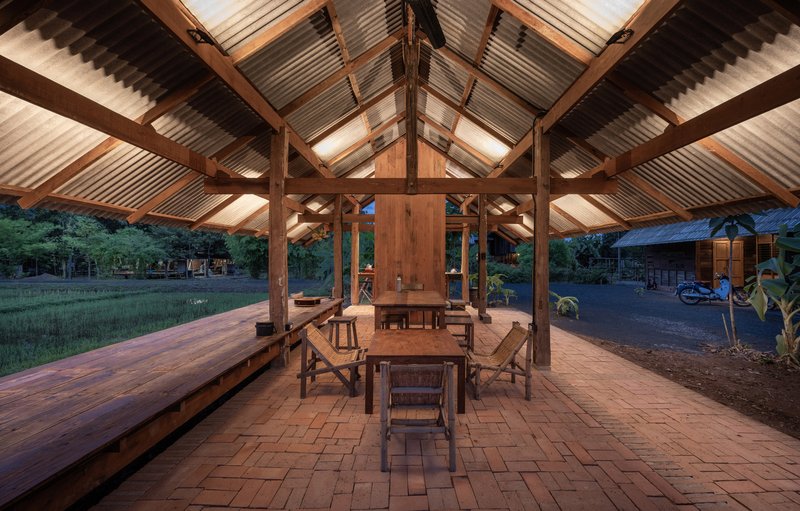 Interior view of timber roof structure with central storage volume and dining area at dusk