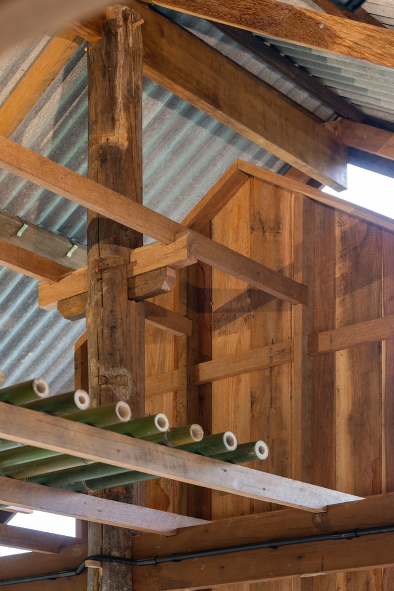 Detail of timber column and beam joinery with corrugated metal roof panels and reclaimed wood wall cladding