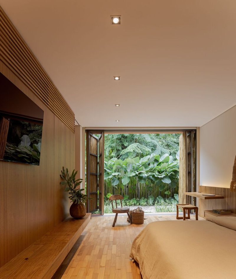 Bedroom with folding timber doors opened to garden planted with banana trees and palms