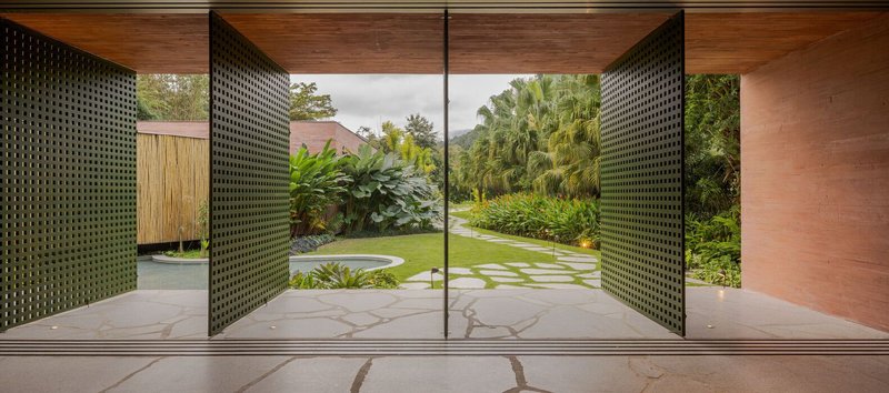 Perforated metal pivot doors framing a view of the stepping stone path through the lawn