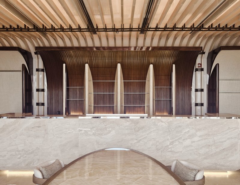 Nalu ground floor: dark timber wave-form columns rising to a slatted ceiling, marble counter, warm lighting