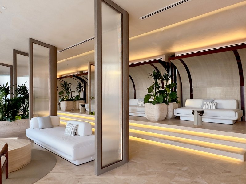 Ilios interior: arched concrete forms with stepped platforms, white sofas, tropical planting, lit cove lines