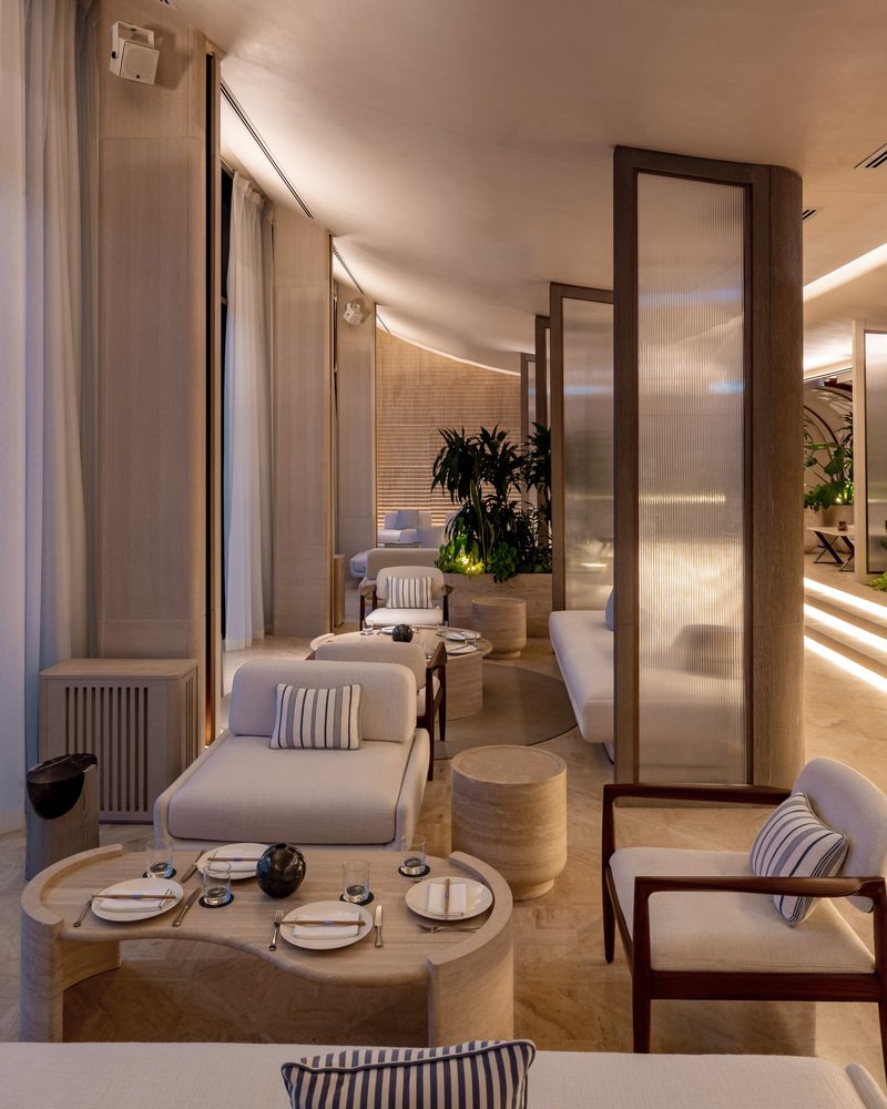 Ilios lounge: curtained alcove seating, low tables, curved ceiling forms, evening atmosphere