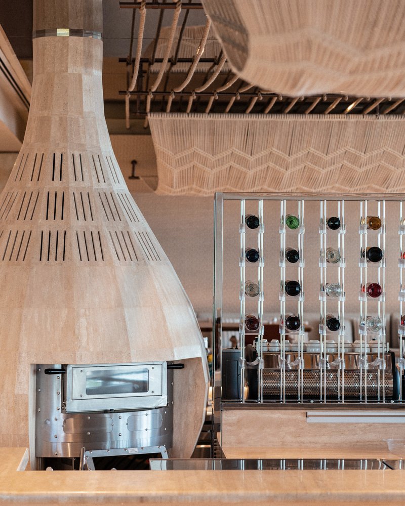 Nalu bar detail: woven timber conical hood over pizza oven, glass bottle display, timber counter