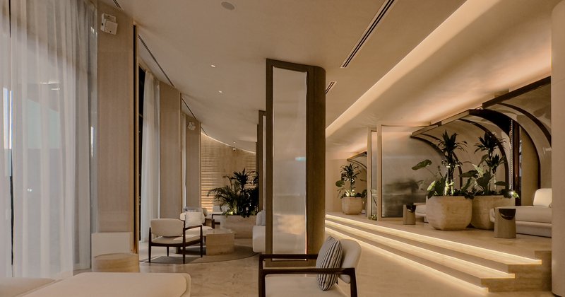 Ilios corridor at night: tall mirrors between arched concrete bays, warm glow, sheer curtains