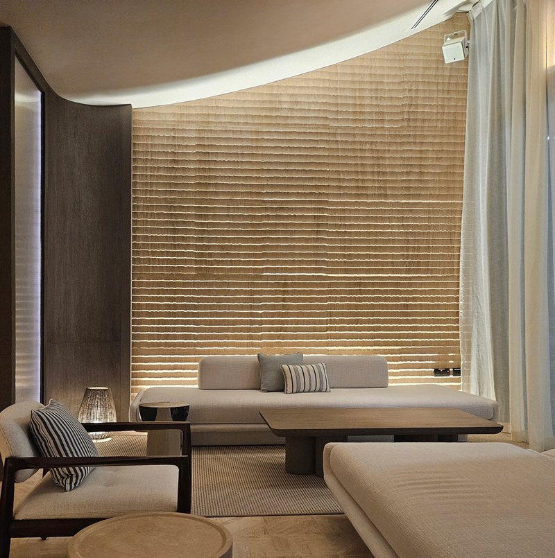 Nalu lounge alcove: woven wall panel behind day bed seating, ambient light, striped cushions