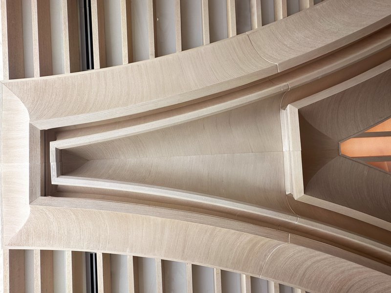 Column detail: looking up at the junction of arched concrete ribs and timber slat ceiling