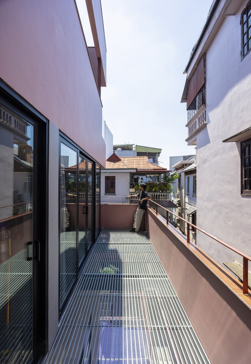 Narrow terrace with metal grating flooring and glazed sliding doors opening to adjacent buildings