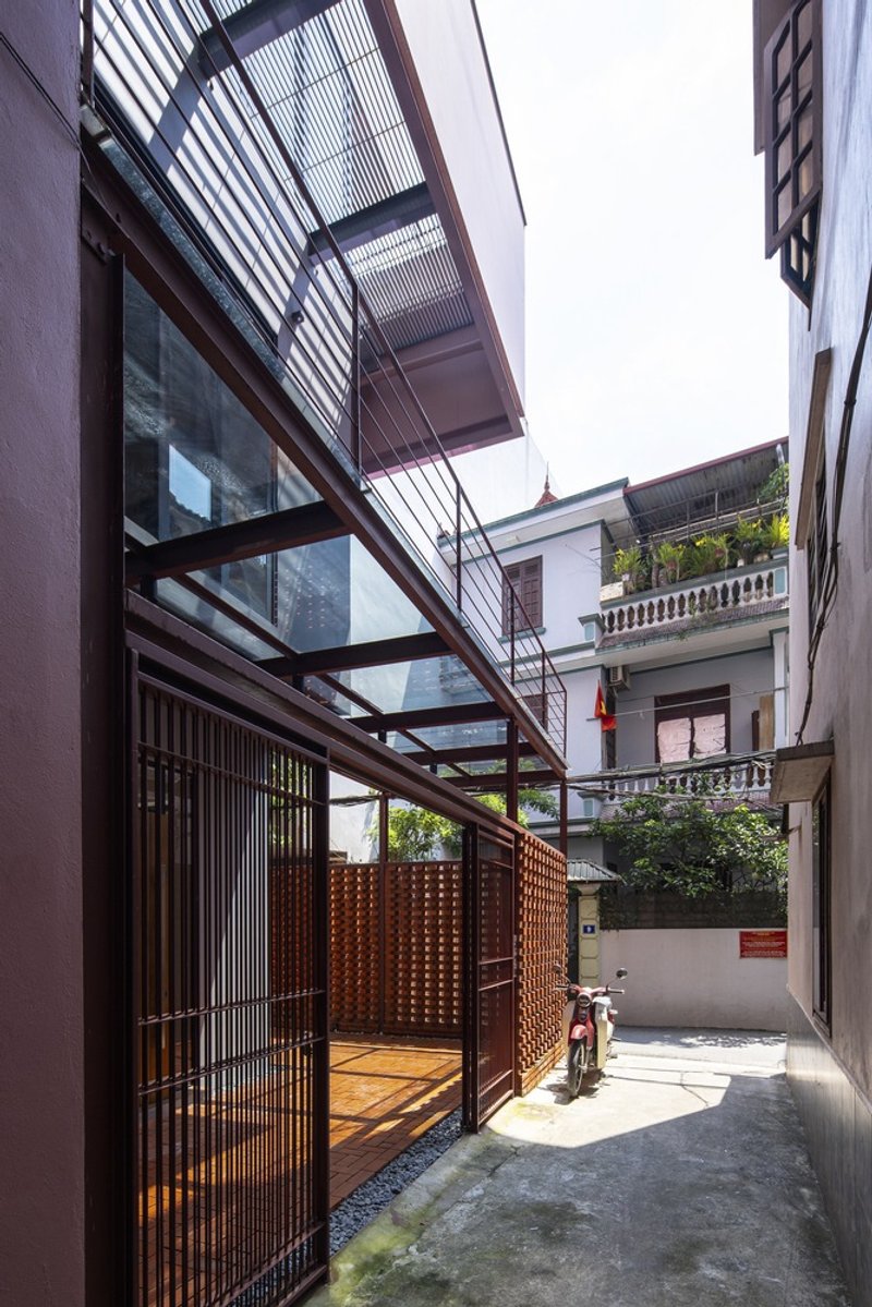 Steel and glass canopy extending over a timber-screened entrance with a motorbike parked beyond