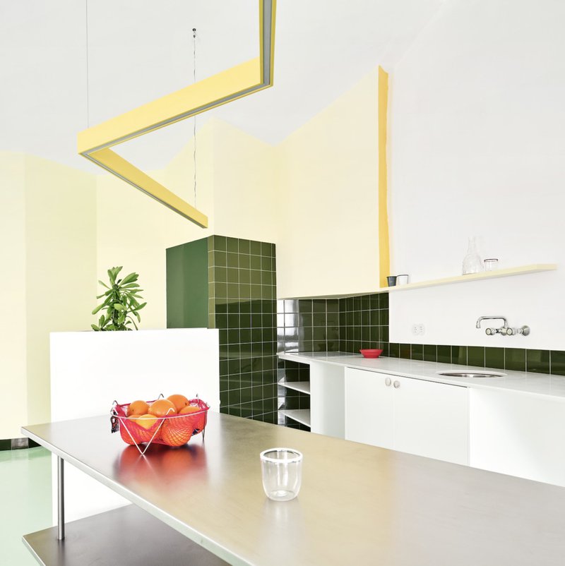 Kitchen with dark green tile column and backsplash, white counters, and a yellow ceiling beam overhead