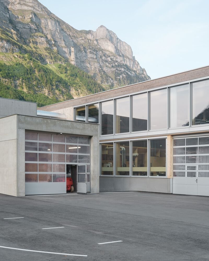 Facade with translucent overhead doors and glazed upper level set against a rocky mountain backdrop