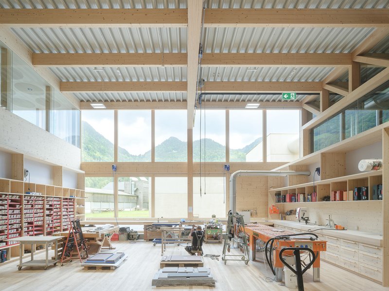 Workshop interior with exposed timber beams, corrugated metal ceiling and floor-to-ceiling windows overlooking mountains
