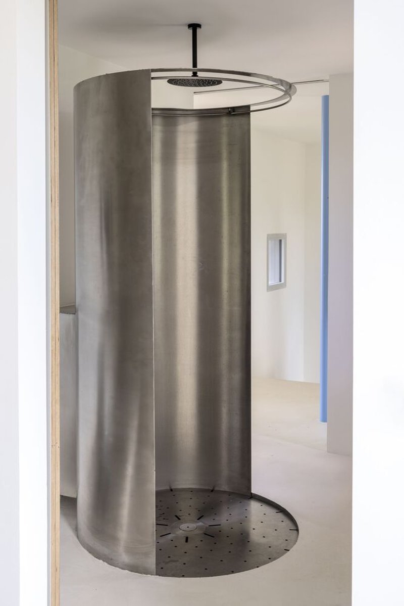 Close view of the curved metal shower screen with overhead rain showerhead and drainage holes