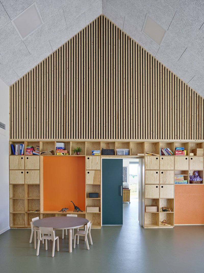 Interior view of plywood storage wall with vertical timber slat gable above and polished concrete floor below