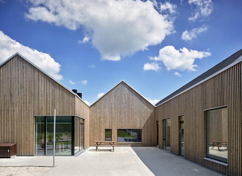 Central courtyard defined by three gabled timber facades with a picnic bench on pale gravel paving