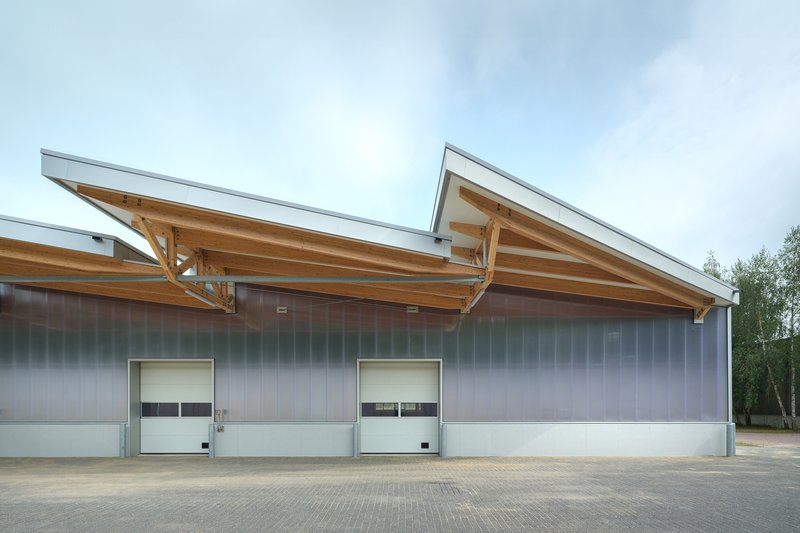 Detail of the sawtooth roof with exposed timber trusses and metal cladding above two loading doors