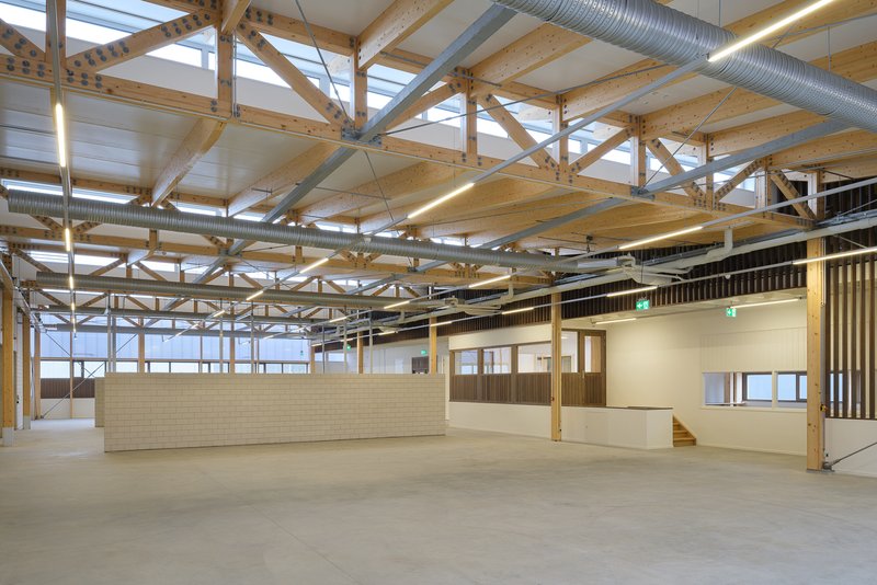 Open hall interior showing exposed timber roof structure with steel bracing and clerestory glazing