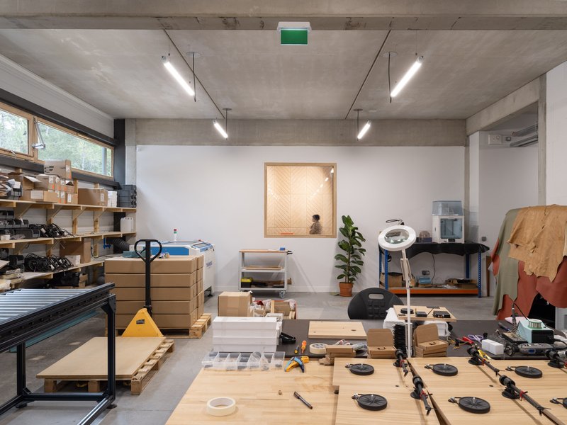 Fabrication room with timber framed window, person seated beyond, and tools scattered on benches