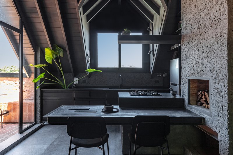 Kitchen with vaulted timber ceiling, black terrazzo island, and doorway opening to brick terrace