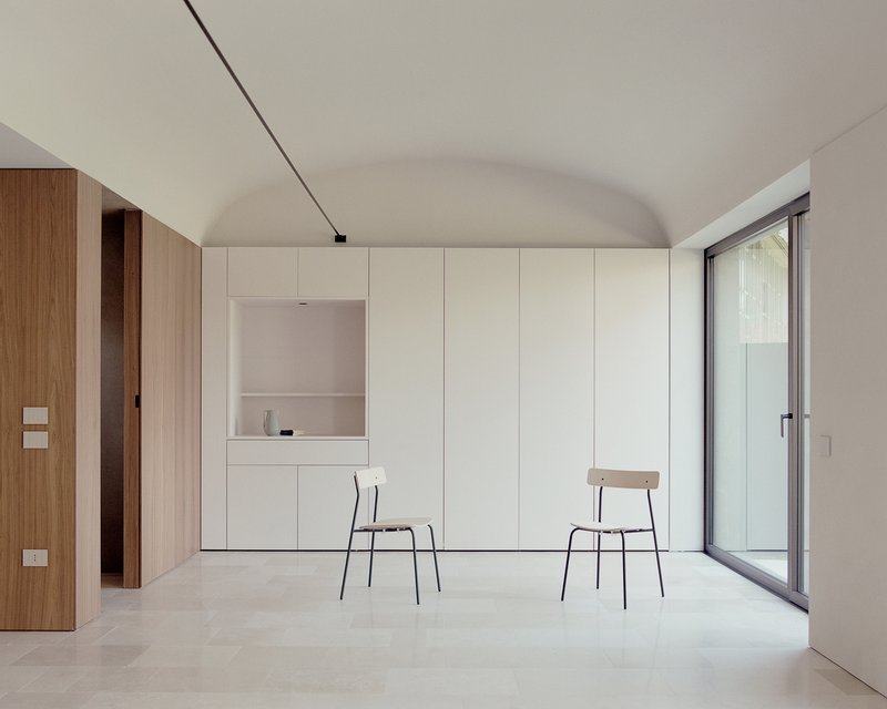 Interior room with white built-in cabinetry, two chairs and vaulted ceiling under soft daylight