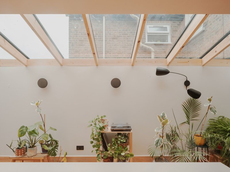 View through the glazed roof structure to the neighboring brick facade and planted shelf below