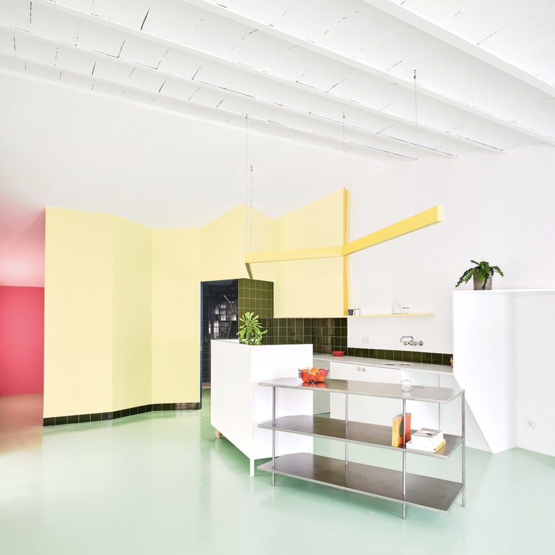 Open kitchen with white exposed ceiling beams, metal shelving unit, and pink room beyond