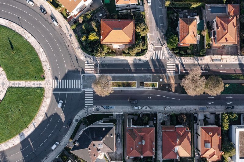 Drone view showing the roof canopy stretching across the roadway between residential buildings with terracotta tiles