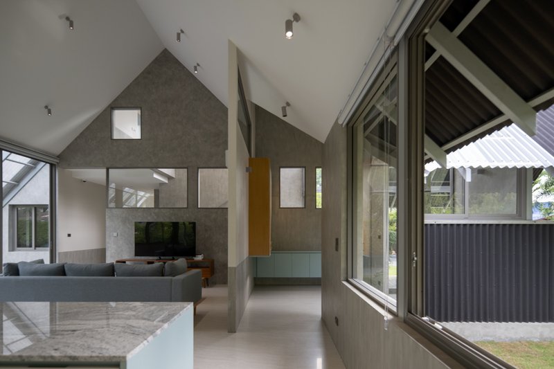 Double-height living space with gabled concrete walls and full-height glazing to the courtyard
