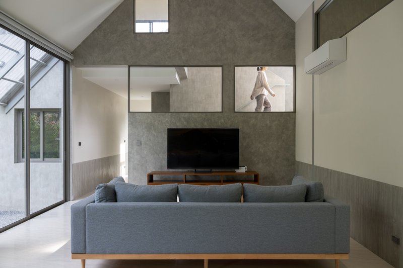 Living room with a concrete wall featuring clerestory openings to the upper level