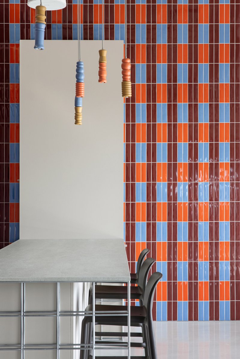 Dining area with blue and orange checkered tile wall and ceramic pendant lights above a table