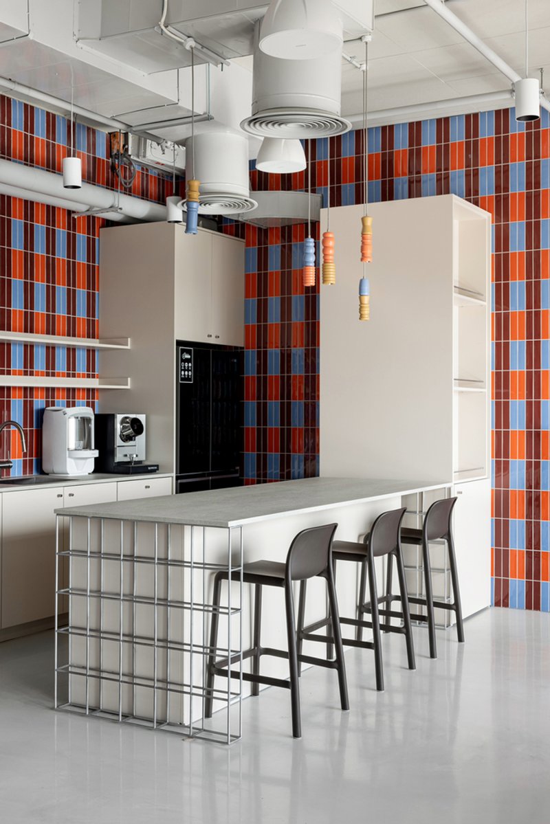 Kitchen island with glass block base surrounded by bar stools under exposed ceiling ductwork