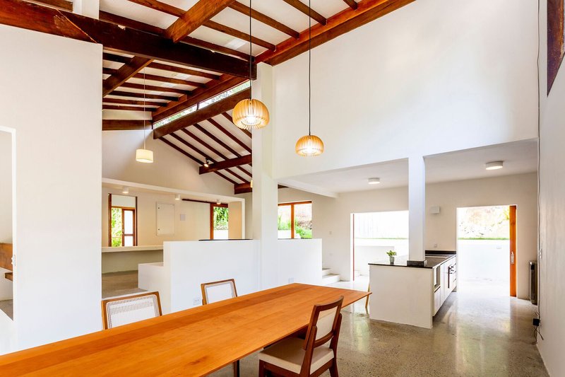 Open-plan dining and kitchen space with timber table under exposed ceiling beams and pendant lights