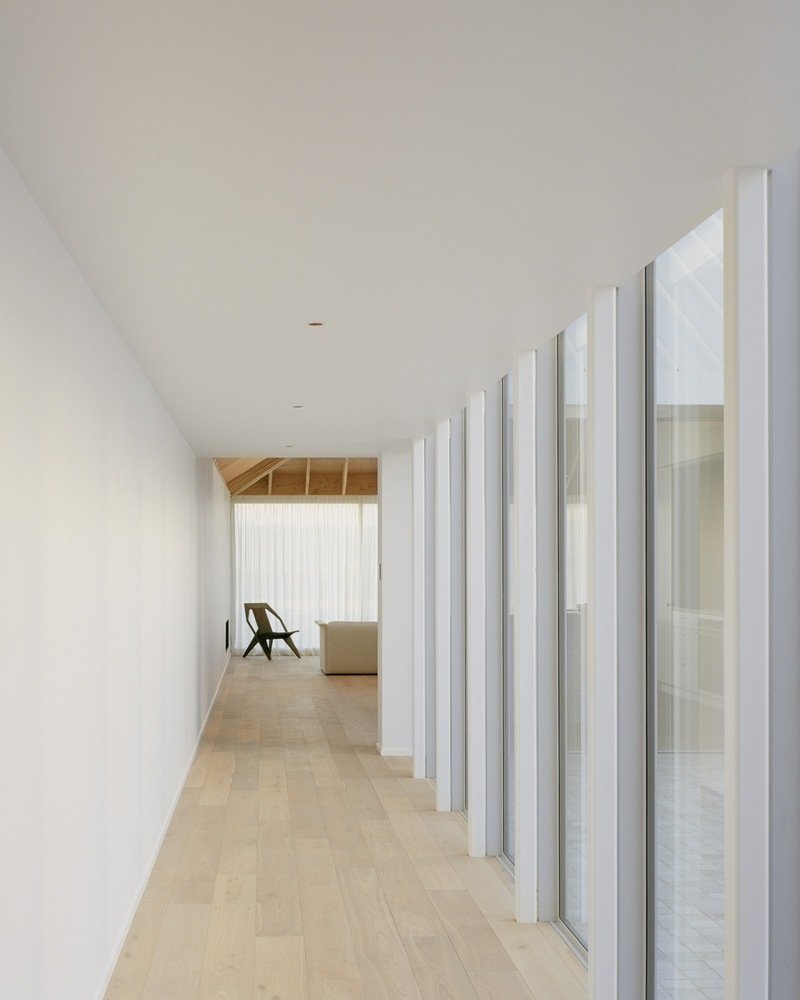 Hallway with vertical white slat partitions along glazed courtyard and pale timber floor