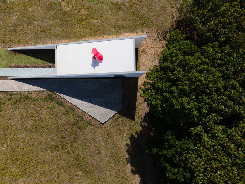 Aerial view of the cantilevered white roof plane with a figure in red walking across the deck