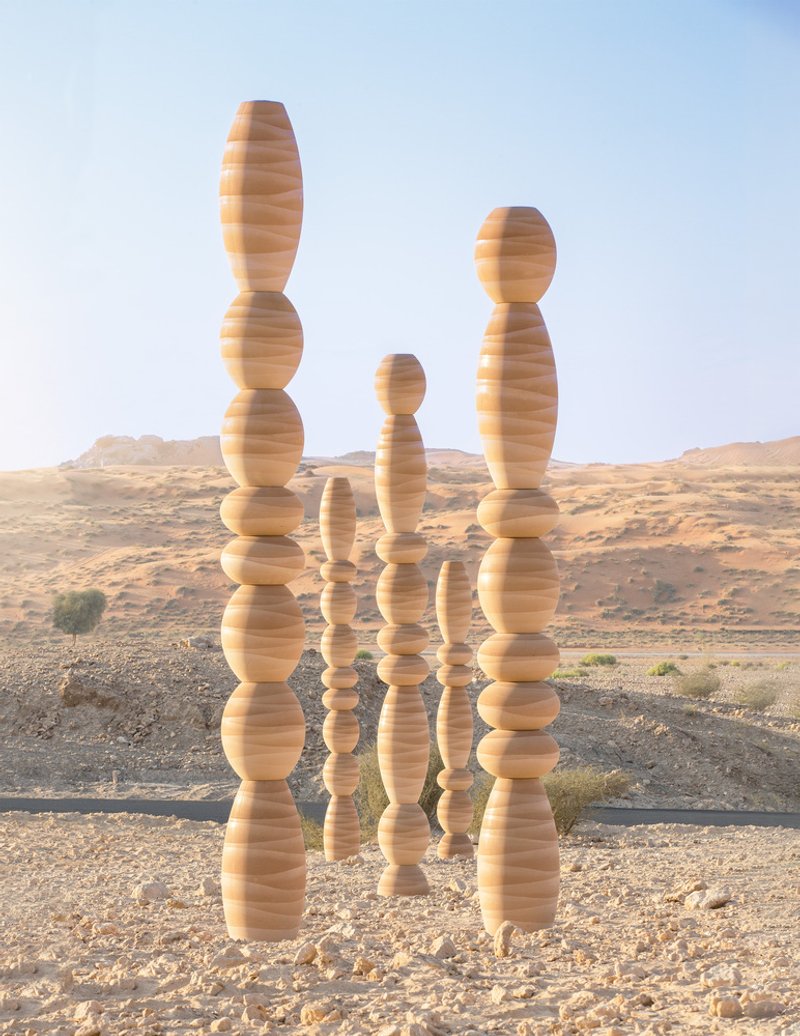 Group of stacked laminated wood columns with spherical and elliptical segments in a desert landscape