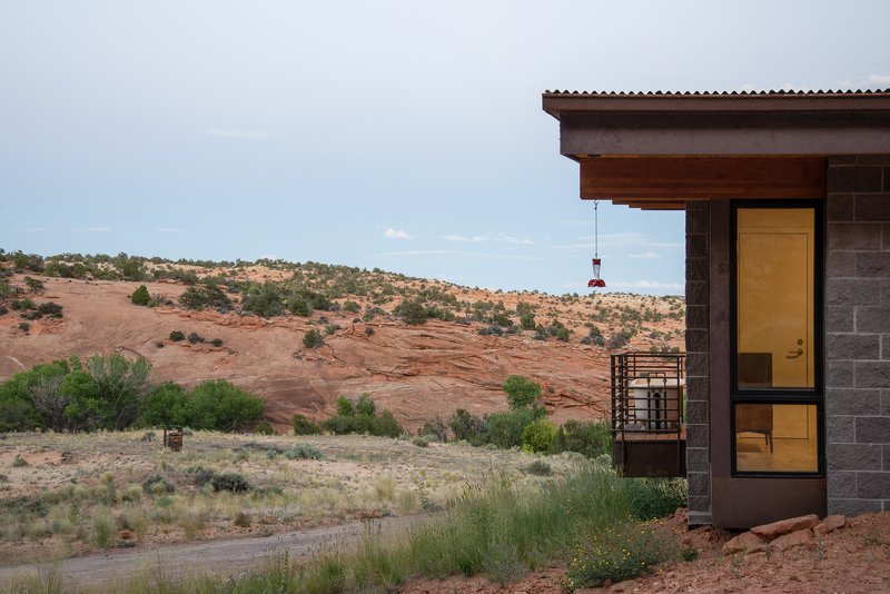 Corner of the concrete block and timber facade with glazed doors opening to the desert landscape