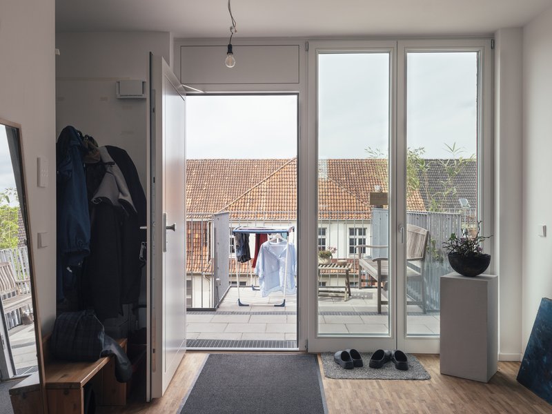 Entry vestibule with glazed doors opening to a rooftop terrace overlooking clay-tiled roofs