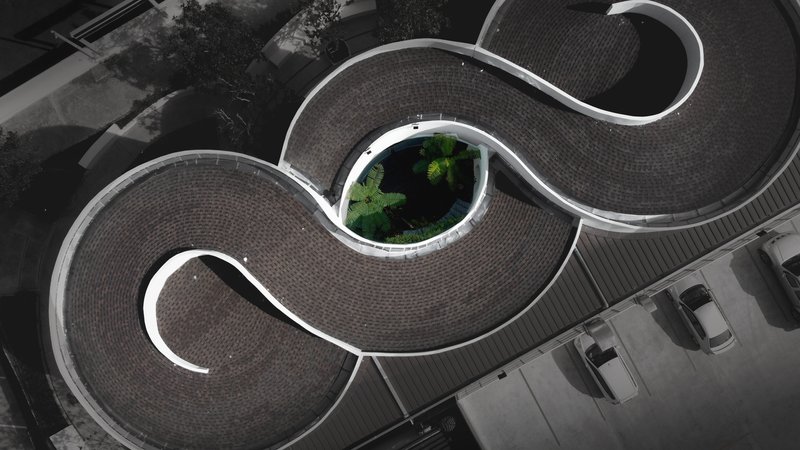 Aerial view of the curved roof with three lobed forms enclosing a central planted courtyard