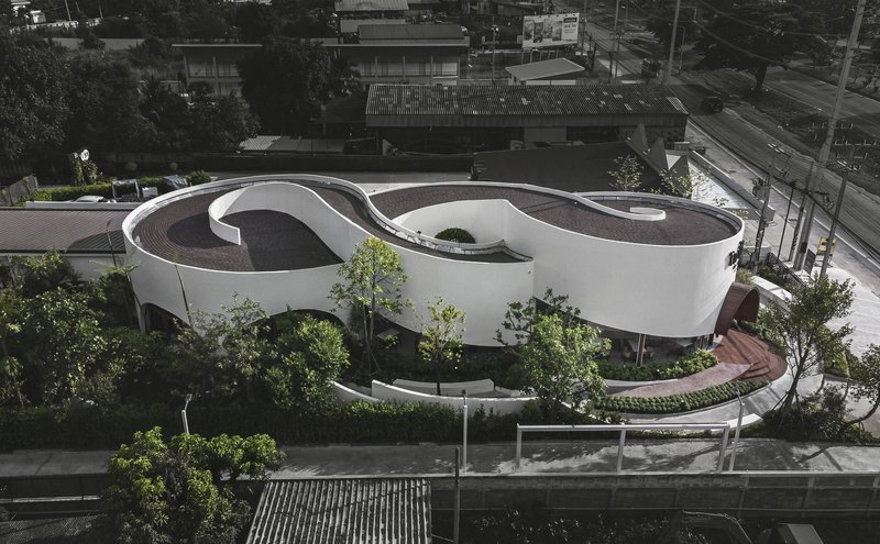 Elevated view of the cloverleaf roof set among trees along a street at dusk