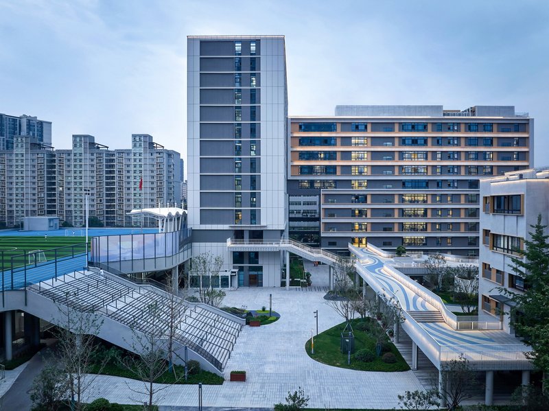 Elevated view of the courtyard with a serpentine pedestrian bridge connecting residential towers at dusk