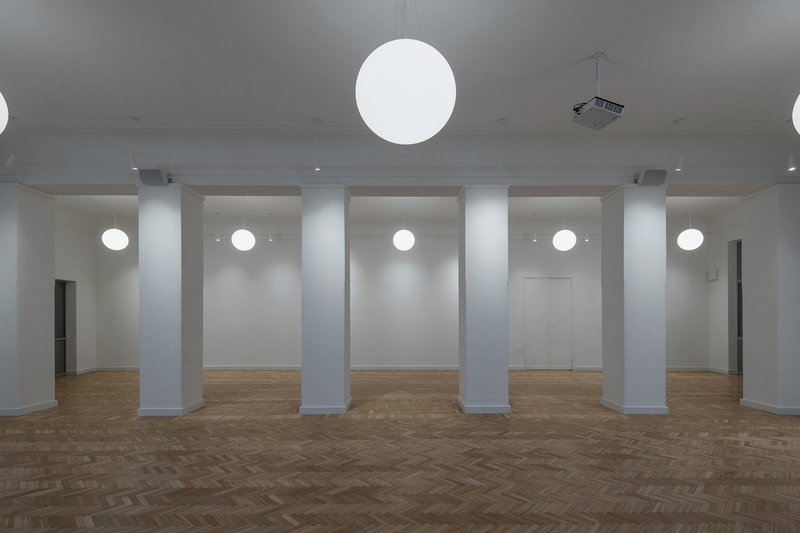 Interior room with herringbone oak flooring, white columns and sphere pendant lights suspended from the ceiling