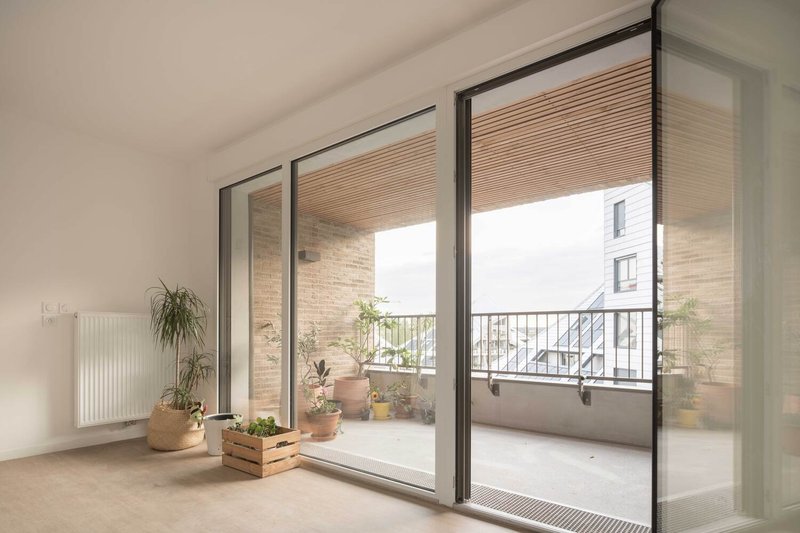 Interior room with sliding glass doors opening onto a balcony with potted plants and metal railing