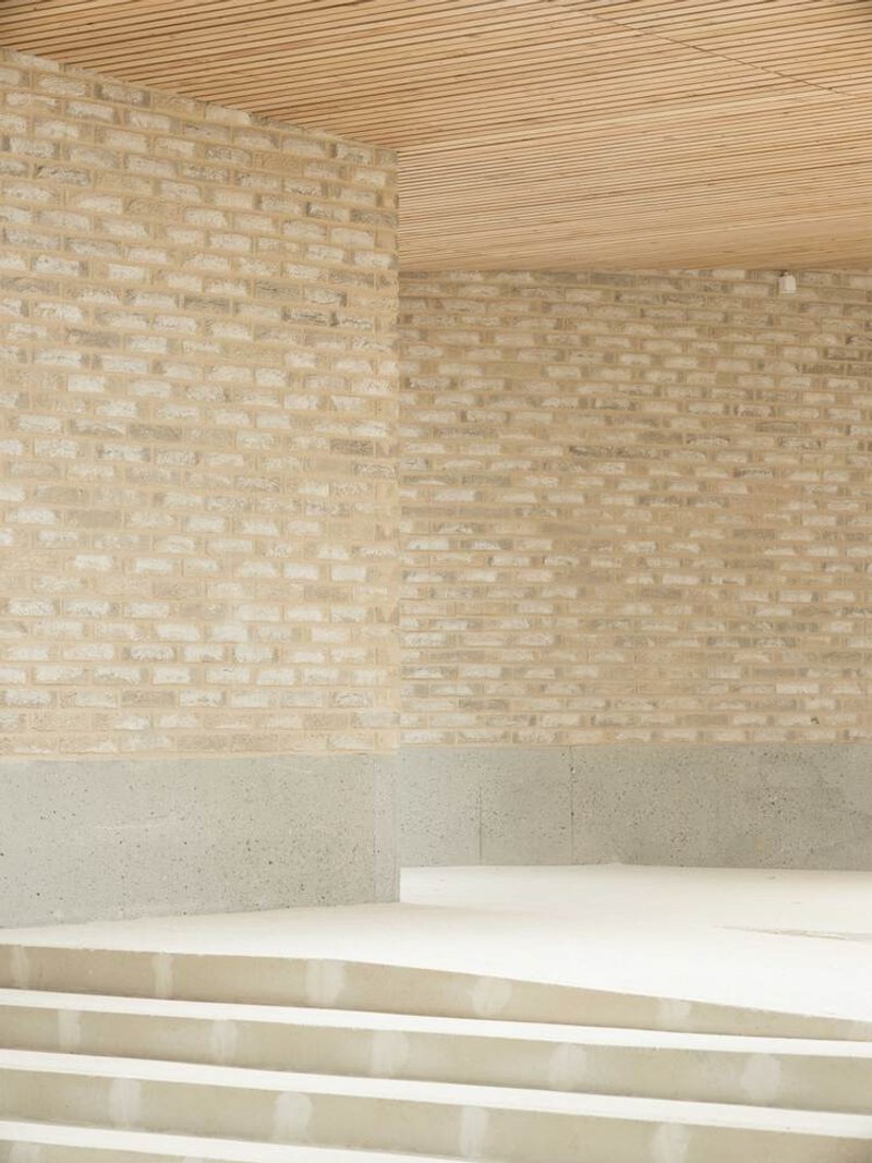 Interior corner showing pale brick walls, timber slat ceiling and terrazzo stairs descending